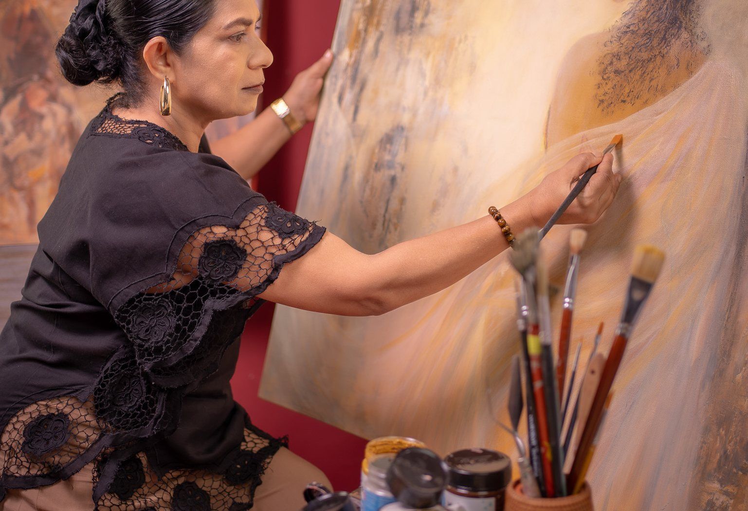 Priyadarshani Tennakoon painting in the studio, one hand steadying the canvas